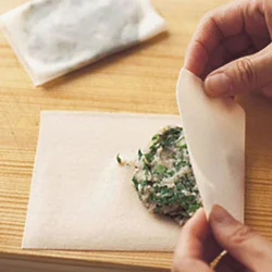半分に切った春巻きの皮に春菊とひき肉、ごま、塩、こしょうを混ぜたものをのせ、両端を折りたたむ。折った面から焼き始めると、はがれない。