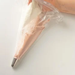 絞り出し袋にいちごクリームを縦半分に入れ、別の袋に入れた生クリームを残り半分に絞る。