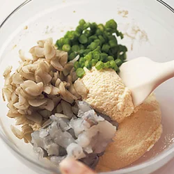 ざるでこした豆腐に調味料などを加えて混ぜたところに、ごぼう、いんげん、えびを加えて混ぜる。