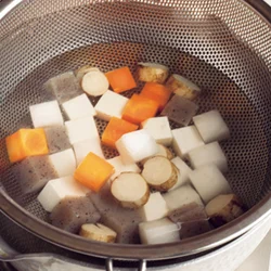 根菜とこんにゃくはざるに入れてさっと湯にくぐらせ、雑味を除く。豚肉も同じ湯にくぐらせて、余分な脂や臭みを除く。
