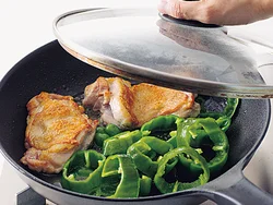 肉の皮面をしっかり焼きつけてから、あいたところにピーマンを入れる。