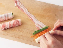 肉は幅広のほうを手前にし、野菜をのせてくるくる巻く。巻き終わりは脂ではなく肉どうしがくっつくようにすると、焼きつけた時にようじなしでも留まる。