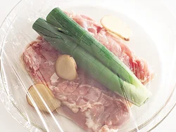 とり肉は厚みを均一にし、皮目を下にして耐熱皿に入れる。ねぎ、しょうがと一緒に加熱し、臭みを取る。