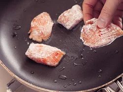 鮭は小麦粉をまぶし、皮目を下にして並べ入れ、パリッとこうばしく焼く。