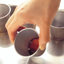 手早くカラメルをプリン型に入れて、固まらないうちにプリン型を傾けるなどして底全体に広げる。手早くしないと型がとても熱くなるので注意。型をバットに並べておくと扱いやすい。