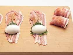 肉は幅広のほうを奥にして置き、みそをぬり、くっつきやすいように小麦粉を薄くふる。しそ、ゆで卵の断面を下にしてのせて巻く。