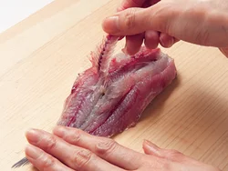尾のつけ根の中骨を折って端を持ち、身を押さえながら静かに骨をはずす。