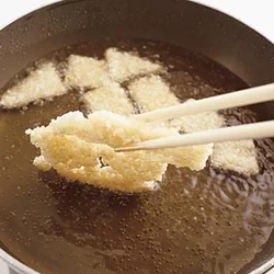 上下を返すときは、おこげどうしがくっついたものはそのままでＯＫ。両面がきつね色になれば、菜箸でつつくだけで簡単に離せる。