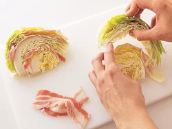 キャベツの葉と葉の間に豚肉をはさみ、バラバラにならないように注意して、くし形のままフライパンに並べる。