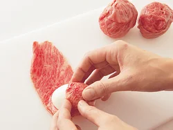 ゆで卵１個に牛肉２枚を使い、白身が見えなくなるように十字に巻きつける。小麦粉をまぶしてはがれにくくする。