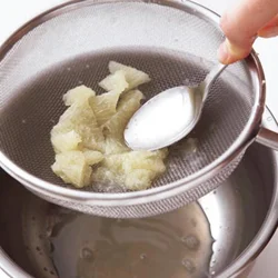 グレープフルーツを薄皮ごとざるにとって、スプーンの背で押すと、むだなく果汁が搾れる。あれば専用の搾り器を使っても。