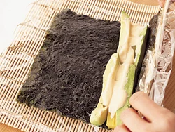 のりが見えないようにご飯をのせて上下を返し、アボカドは横２列、たくあんは横１列に置く。