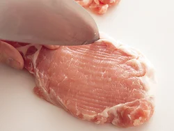 赤身と脂身の間の筋を、包丁の先を使って肉の繊維に垂直に切る。焼いて身が縮んだり反り返るのを防げる。