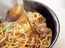 野菜や肉などの具と炒めた麺を器に盛り、スープを注ぐ。