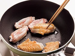 手羽中はフライパンに皮目を下に並べ入れ、こんがりと焼きつける。煮くずれを防ぎ、カリッとした食感になる。