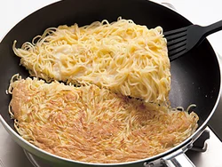 麺はこんがり焼き色がついたら上下を返す。返しやすくするために、半分に切ってから１切れずつ返す。