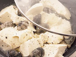 酒を控えめにして豆腐の水分で蒸し煮にするので、あさりのうまみが凝縮した一皿に仕上がる。