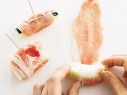 豚肉の手前に野菜をのせ、くるくると巻いて。巻き終わりをようじで留めるとはがれにくく、ころももつけやすい。
