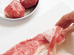 おにぎりは肉が巻きやすいように三角に握る。表面がすべて肉でおおわれるように、肉を広げておにぎりを回転させながら巻きつけていくとよい。