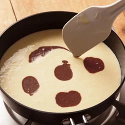 ゴムべらの先端でマーブル模様を描く。ゴムべらを深く入れるとチョコレートソースが沈みやすくなるので表面をなぞるようにして。