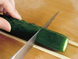 きゅうりに沿って割り箸を添えると均一の深さに切れるため、難しい蛇腹切りも簡単にできる。