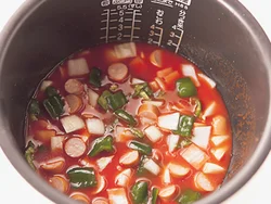 材料を炊飯器に入れてトマトジュースで炊くだけ。均一に火が通るよう、具材をまんべんなく散らして。