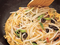 卵液は菜箸で手早くかき混ぜながら焼くと、短時間で火が通る。周囲が焼き固まったら端に寄せて、フライパンより一回り小さく形を整えながら焼く。