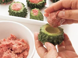 ゴーヤーはスプーンで種ごとわたを除き、肉だねを６等分して手のひらで軽く丸め、ゴーヤーの穴に押し込む。