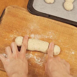 左右の端から3cmのところに指を置き、転がしてくびれを作る。発酵後にふくらんでくびれが消えたら、もう一度同じようにして。