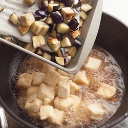 煮汁が煮立ったところに揚げた豆腐、続けてなすを戻し入れる。煮るうちに、豆腐にまぶした粉類で全体にとろみがつく。