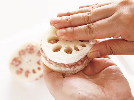 2枚のれんこんで肉だねをはさんだら両手でぎゅっと押さえ、れんこんの穴の中まで肉だねをたっぷり詰める。