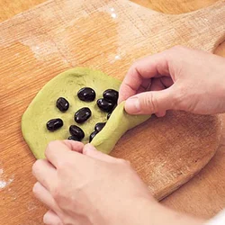 「豆ロック」の作り方を参考にして、生地を広げ、黒豆をのせて巻き、さらに縦長の向きにしてうず巻き状に巻いて。