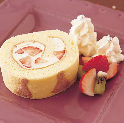 でき上がったデコロールを切り分けて、さらにかわいく盛りつければ華やかに。デコロールを柄に合わせて切って皿に盛る。作り方７のクリームを少々取り分けて星口金をつけた絞り出し袋に入れ、モミの木に見立て、クリームを3段重ねて絞り出す。同じように2段絞って小さいモミの木も作り、アラザン適宜を飾り、好みでカットしたいちごやキーウィを添えても。
