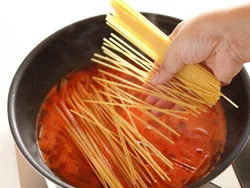 スパゲッティはソースの水分でゆでていく。半分に折って加えればフライパンからはみ出さずにゆでられる。
