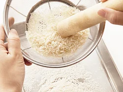 パン粉はざるでこして細かくする。こうすると、ころもの表面積が小さくなるので、油の吸収量を減らすことができる。