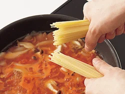スパゲッティは半分に折って加えるとはみ出さず、効率よく煮られる。