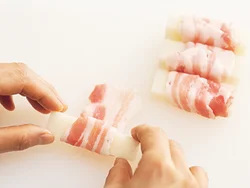 もちに豚バラ肉をくるくると巻く。肉のうまみがもちにしみておいしくなる。