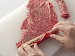 牛肉の両端からごぼうがはみ出ないように、端を折りたたみながら巻きつける。肉が小さい場合は何切れかをつなげて、厚みが均等になるように巻く。