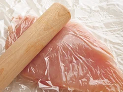 とり肉はラップ２枚ではさみ、めん棒でたたいてのばすと、火が通りやすくなり、洗いものも少なくなる。