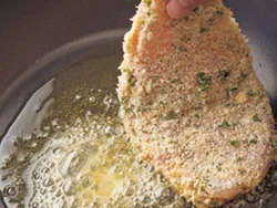 薄くのばしたとり肉に細かく砕いたパン粉をつけると、少ない油でも均一にむらなく揚げ焼きができる。