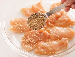 広げたとり肉の両面に白いりごまをふり、手で軽く押さえる。肉に片栗粉をまぶしているのでしっかりつきやすい。