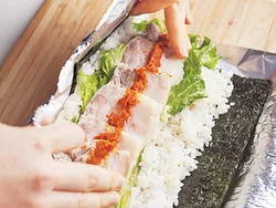 切ったときにのの字になるように巻くのがコツ。巻きすでもできるが、アルミホイルだと形を整えるときに安定する。