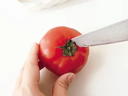 へたを包丁の先でくりぬいてから、トマトの上下を少しずつ切り、トマトが倒れないように立てて器に置く。