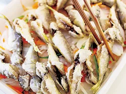 玉ねぎを広げた上に揚げたての豆あじをのせる。熱が伝わり、水にさらさなくても、玉ねぎの辛みがやわらぐ。
