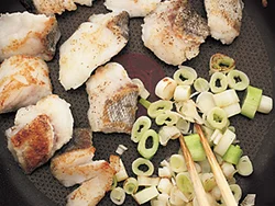 たらを焼いているフライパンのあいたところでねぎも炒める。ねぎは炒めることで甘みが出て、ソースと合わせたときに一体感が生まれる。