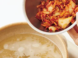 だし汁が煮立ったらキムチを加える。キムチは賞味期限に近い発酵の進んだものが、酸味とコクが強く、加熱するとおいしい。