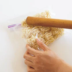 厚手の保存袋にラーメンを入れてめん棒でたたいて細かく砕くと、スープをたっぷりと吸いやすくなる。