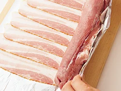 豚肉の端の細い部分は、内側に折り込んで太さを均一にすると巻きやすい。また、ベーコンを巻くときは、豚肉を中に押し込むようにして巻くとうまくいく。
