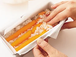 鮭フレークのすし飯を、すき間を埋めるように手でしっかり押さえながら詰めると、形くずれしにくいすしケーキができる。