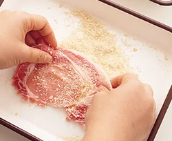 豚肉に薄くオリーブ油をぬり、それをのりにしてパン粉を表面に薄くつける。中にオリーブ油をぬることで、焼くときの油も少なくできる。